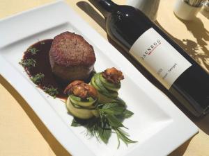 a white plate with a piece of food and a bottle of wine at Enzianhof in Ligist