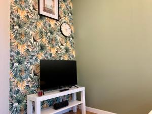 a living room with a tv and a clock on a wall at Superbe appartement avec parking gratuit sur place in Saint-Denis