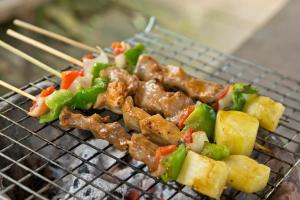 a group of meat and vegetables on a grill with chopsticks at Hmong Hilltribe Lodge in Chiang Mai