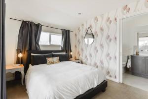 Dormitorio con cama blanca y pared con estampado cardíaco en By The Seaside en Mornington