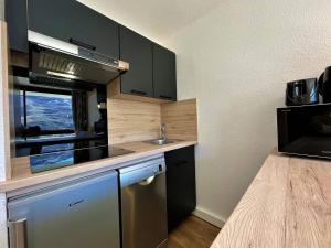 eine Küche mit schwarzen Schränken, einem Waschbecken und einem Fenster in der Unterkunft Appartement Les Menuires, 2 pièces, 4 personnes - FR-1-452-270 in Les Menuires