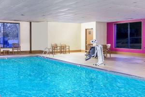 - une piscine dans un hôtel avec des chaises et une table dans l'établissement Baymont by Wyndham Waukesha, à Waukesha