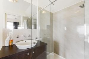 a bathroom with a sink and a glass shower at By The Seaside in Mornington