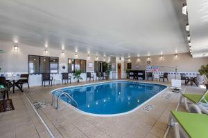 una piscina en una habitación de hotel con mesas y sillas en Comfort Inn & Suites Waterloo - Cedar Falls, en Waterloo