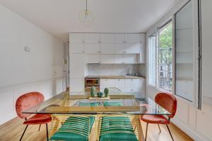 una cucina con tavolo in vetro e 2 sedie di Appartement parisien lumineux proche métro a Clichy