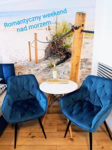 two chairs and a table in front of the beach at Porta Mare Marine in Dziwnów