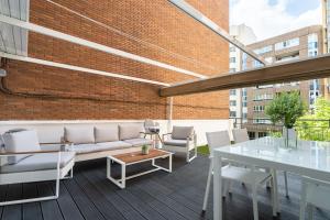 a rooftop patio with white furniture and a brick wall at Apartamento Mani en Avenida España con terraza in Albacete