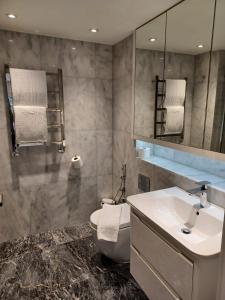 Buckingham Palace Residences by Q Apartments في لندن: حمام مع حوض ومرحاض ومرآة