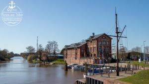 a building next to a river with boats in it at Residenz Whg 2 in Norddeich