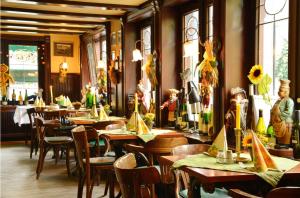 un restaurante con mesas y sillas de madera y ventanas en Hotel Stoffels, en Schmallenberg