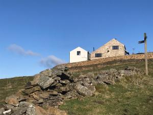 a white house on top of a stone wall at Writers Cottage - Uk33475 in Nenthead