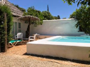 una piscina frente a una casa con sombrilla en Casa Cueva El Naranjo Rocabella, en El Chorro