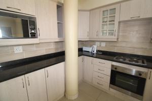 uma cozinha com armários brancos e bancadas pretas em Saints View Resort Unit 1 em Uvongo Beach