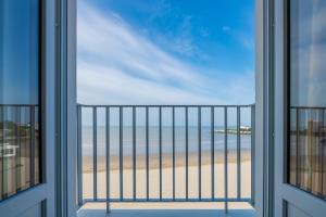 a room with a view of the beach from a balcony at CERISE Royan - Le Grand Hôtel de la Plage in Royan