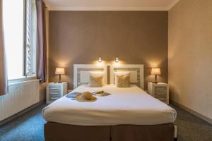 a bedroom with a large white bed with two lamps at CERISE Royan - Le Grand Hôtel de la Plage in Royan