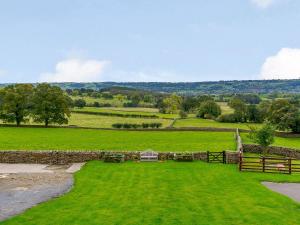 a large green field with a stone wall and a fence at Middle Mistal in Stainburn
