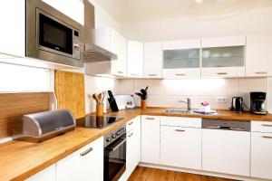 a white kitchen with white cabinets and a microwave at Traumfängerloge -Hafenresidenz in Waren