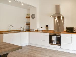 a kitchen with white cabinets and a sink and a stove at Redstones Cottage in Greasby