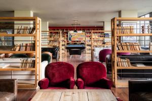 een bibliotheek met twee stoelen en boekenplanken bij Rooms Hotel Kazbegi in Kazbegi