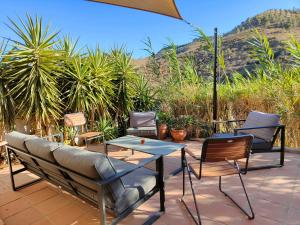 a patio with chairs and a table and a couch at Cortijo Vacas Gordas Villas in Castell de Ferro