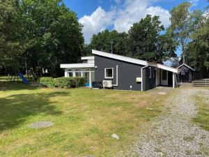 una pequeña casa gris con un patio en 7 person holiday home in rsted, en Kare