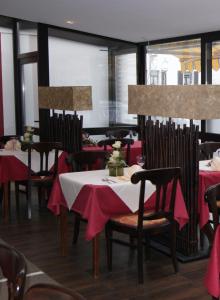 a dining room with tables and chairs with red table cloth at Hotel-Restaurant Bürgerstuben in Lebach