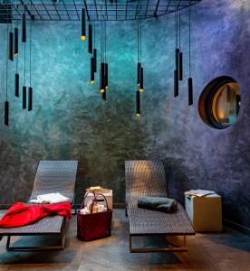 ツェル・アム・ゼーにあるホテル ラティーニの椅子2脚、鏡、シャンデリアが備わるお部屋