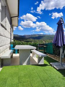 a patio with a table and an umbrella and grass at Vista Estrelada in Requeixo