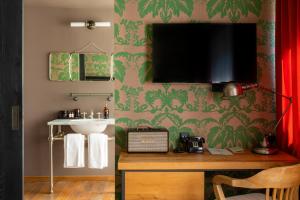 a bathroom with a sink and a television on a wall at Rooms Hotel Tbilisi in Tbilisi City