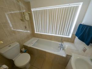 a bathroom with a toilet and a tub and a sink at NEWTON HEATH APARTMENT -750mtrs to beach - Spacious ground floor - Sleeps 6 in Porthcawl
