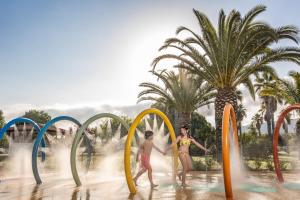 2 personnes sautant dans l'eau d'un parc aquatique dans l'établissement Falkensteiner Club Funimation Garden Calabria, à Curinga