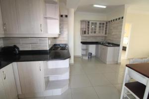 a kitchen with white cabinets and black counter tops at Saints View Resort Unit 3 in Uvongo Beach