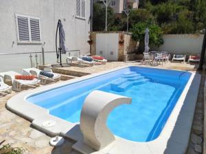 a large blue swimming pool with chairs and a table at Apartments Sollis in Trogir