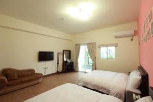 ein Schlafzimmer mit zwei Betten, einem Fernseher und einer Couch in der Unterkunft Dali Moonlight B&B in Taitung