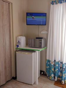 a tv on a wall above a table with a refrigerator at Droom Verlore in Jeffreys Bay