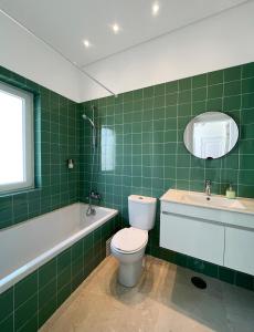 Baño de azulejos verdes con aseo y lavamanos en New Art Apartment en Lisboa