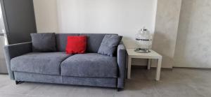 um sofá azul com uma almofada vermelha ao lado de uma mesa em A casa da Joy em Turim