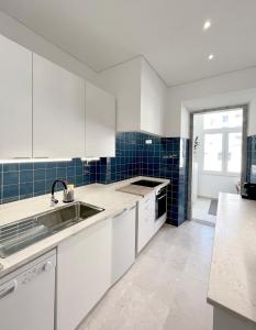 una cocina con armarios blancos y azulejos azules en New Art Apartment en Lisboa