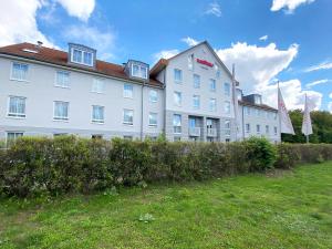 ein großes weißes Gebäude mit einem Grasfeld davor in der Unterkunft DORMERO Hotel Hoyerswerda in Hoyerswerda