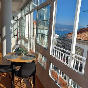 una mesa y sillas en una habitación con ventanas grandes en Loft Turístico, en Vigo