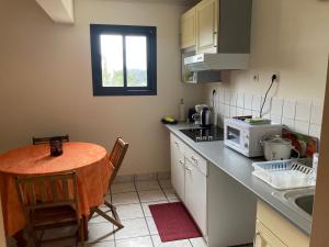 a small kitchen with a table and a microwave at Locations saisonnières The VOLCANO in Le Tampon