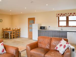 a living room with a couch and a kitchen at Quails Nest in Edlingham