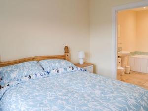 a bedroom with a bed with a blue comforter at Quails Nest in Edlingham