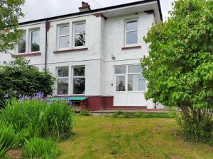 Cette maison blanche dispose de fenêtres et d'une cour. dans l'établissement Buckieburn, à Banknock