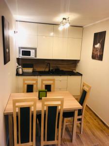 cocina con mesa de comedor de madera y sillas en Apartament Bajka, en Krynica-Zdrój
