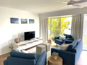 a living room with two blue couches and a television at 2 Bedroom Ground Level Villa in Tropical 4* Resort in Noosaville