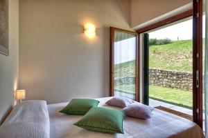 um quarto com uma cama com almofadas verdes e uma janela em Agriturismo Il Pianetto em Verona
