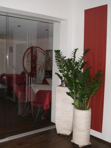 a plant in a white vase next to a dining room at Hotel-Restaurant Bürgerstuben in Lebach