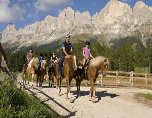 a group of people riding horses down a dirt road at Angerle Alm Apt Rosengarten in Carezza al Lago