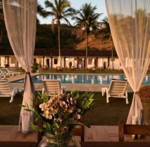 a vase of flowers on a table in front of a pool at Hotel Fazenda Santa Helena in Simão Pereira